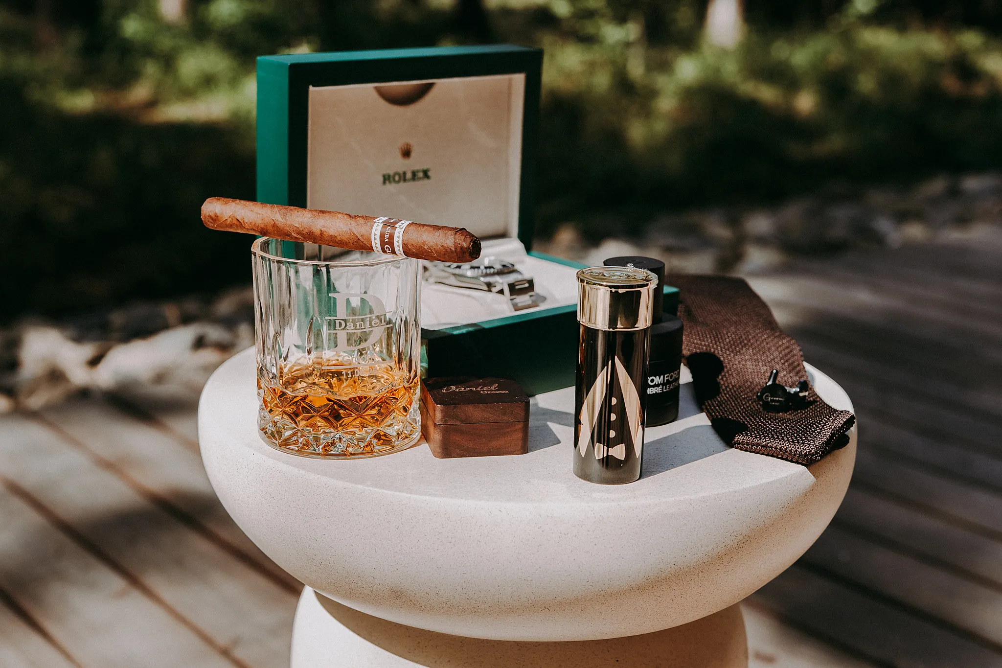 Detale ślubne Pana Młodego: zegarek, perfumy i obrączki na drewnianym stole w domku – Studio Grygierczyk