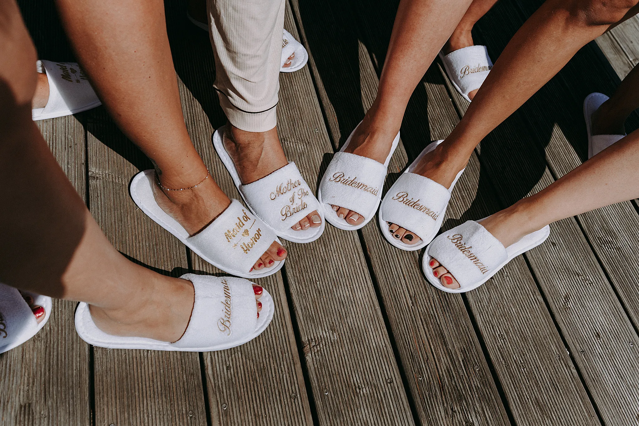 Druhny i panna młoda w szlafrokach wznoszą toast szampanem na tarasie domku w Hotelu Bajka