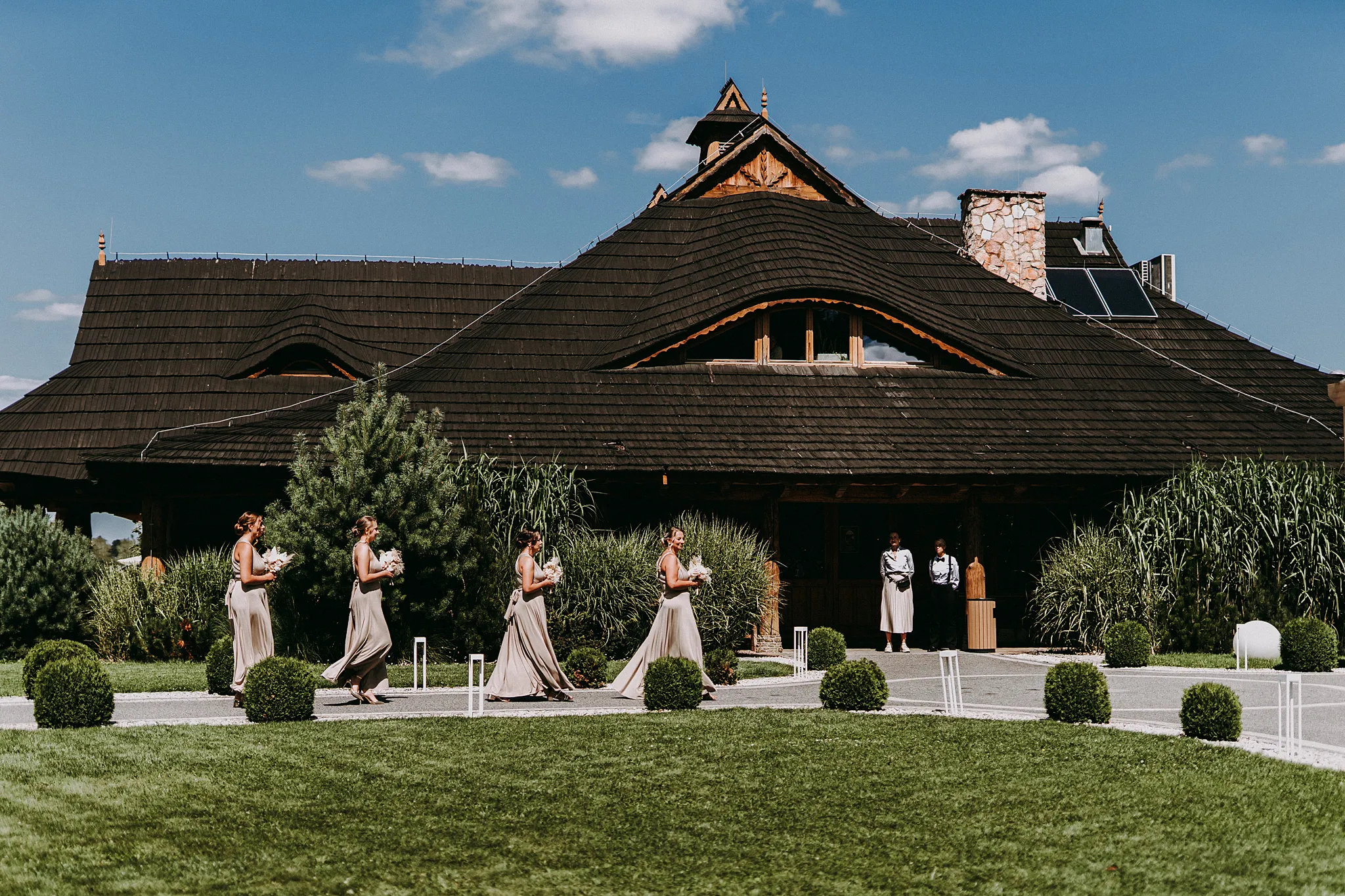 Uśmiechnięte druhny w sukienkach o ciepłych odcieniach towarzyszące pannie młodej w słoneczny dzień