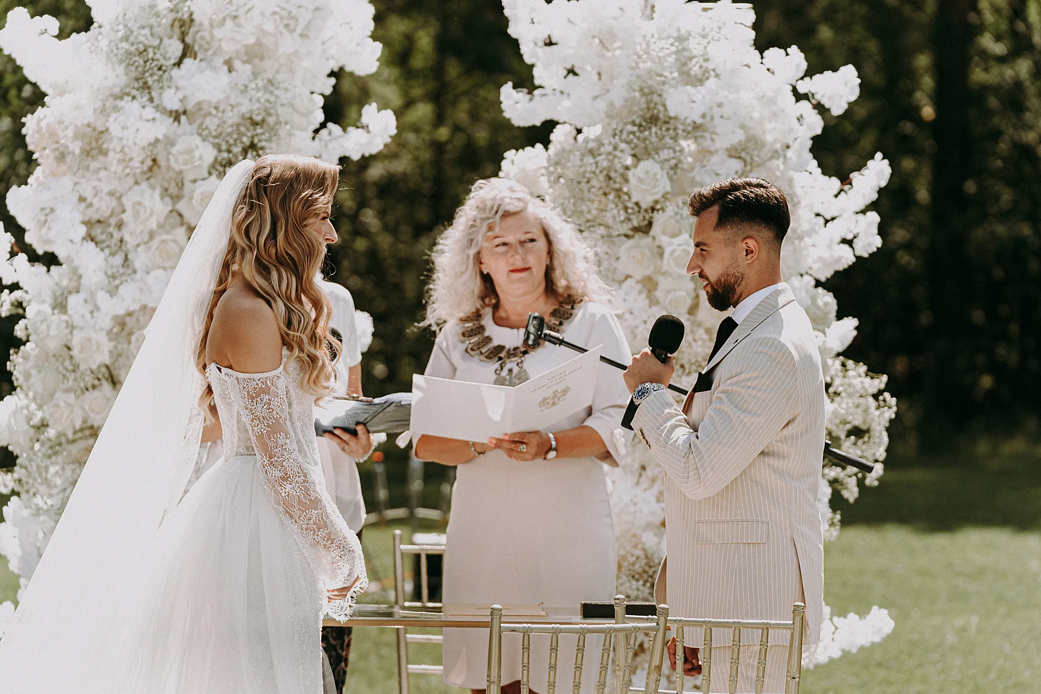 Emocjonalny moment przysięgi małżeńskiej w otoczeniu białych dekoracji i zieleni – fot. Studio Grygierczyk