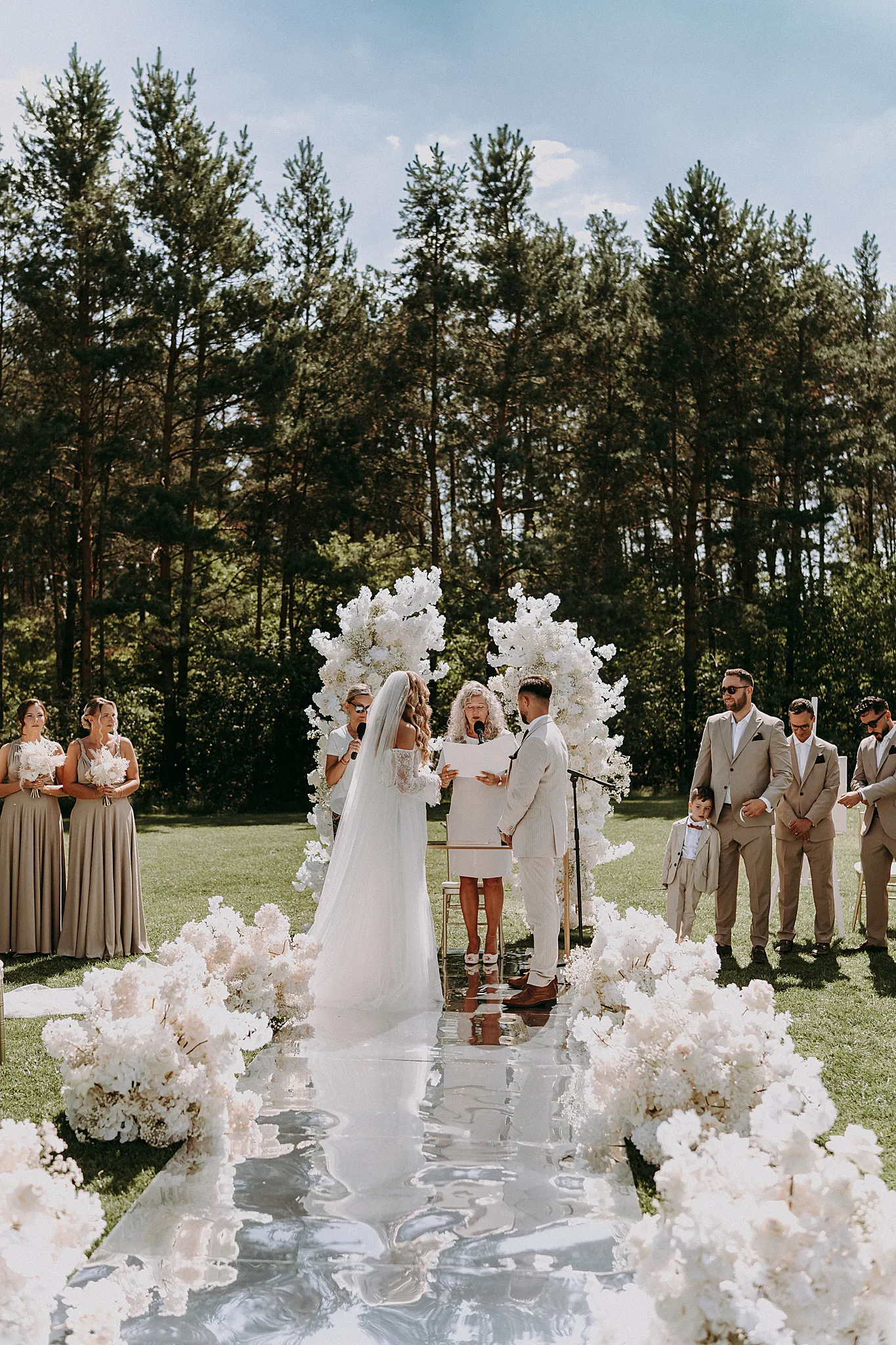 Minimalistyczny, biały ołtarz ślubny na tle błękitnej wody i słonecznego nieba w Grodźcu