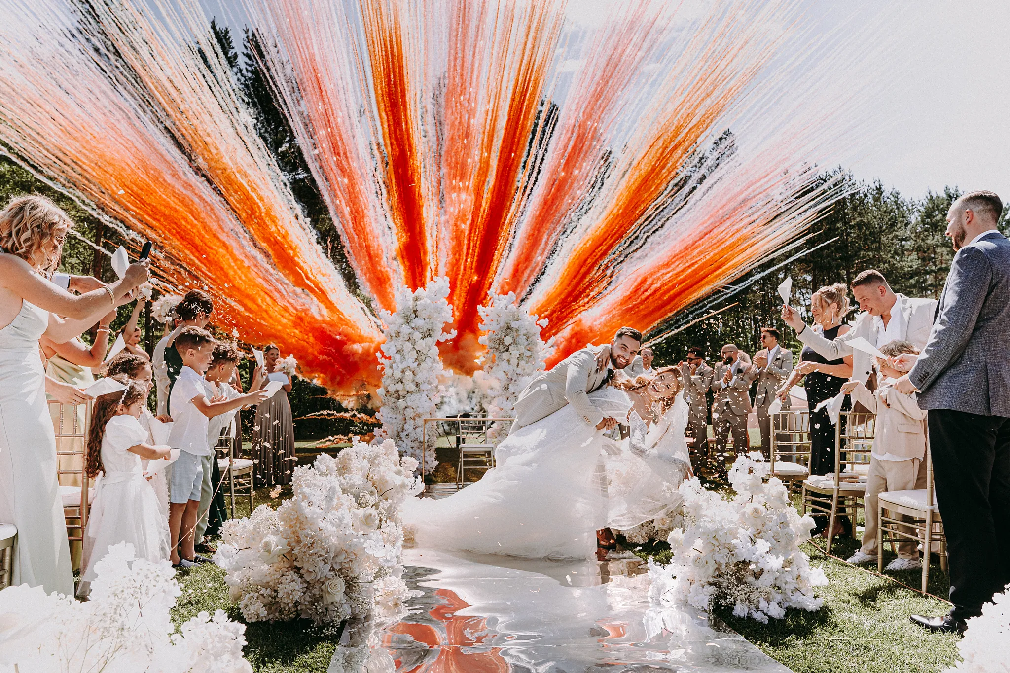 owożeńcy idący wśród kolorowych dymów i rac po ceremonii ślubnej w Hotelu Bajka – Studio Grygierczyk intensywne kolory rac dodaja efektu wow