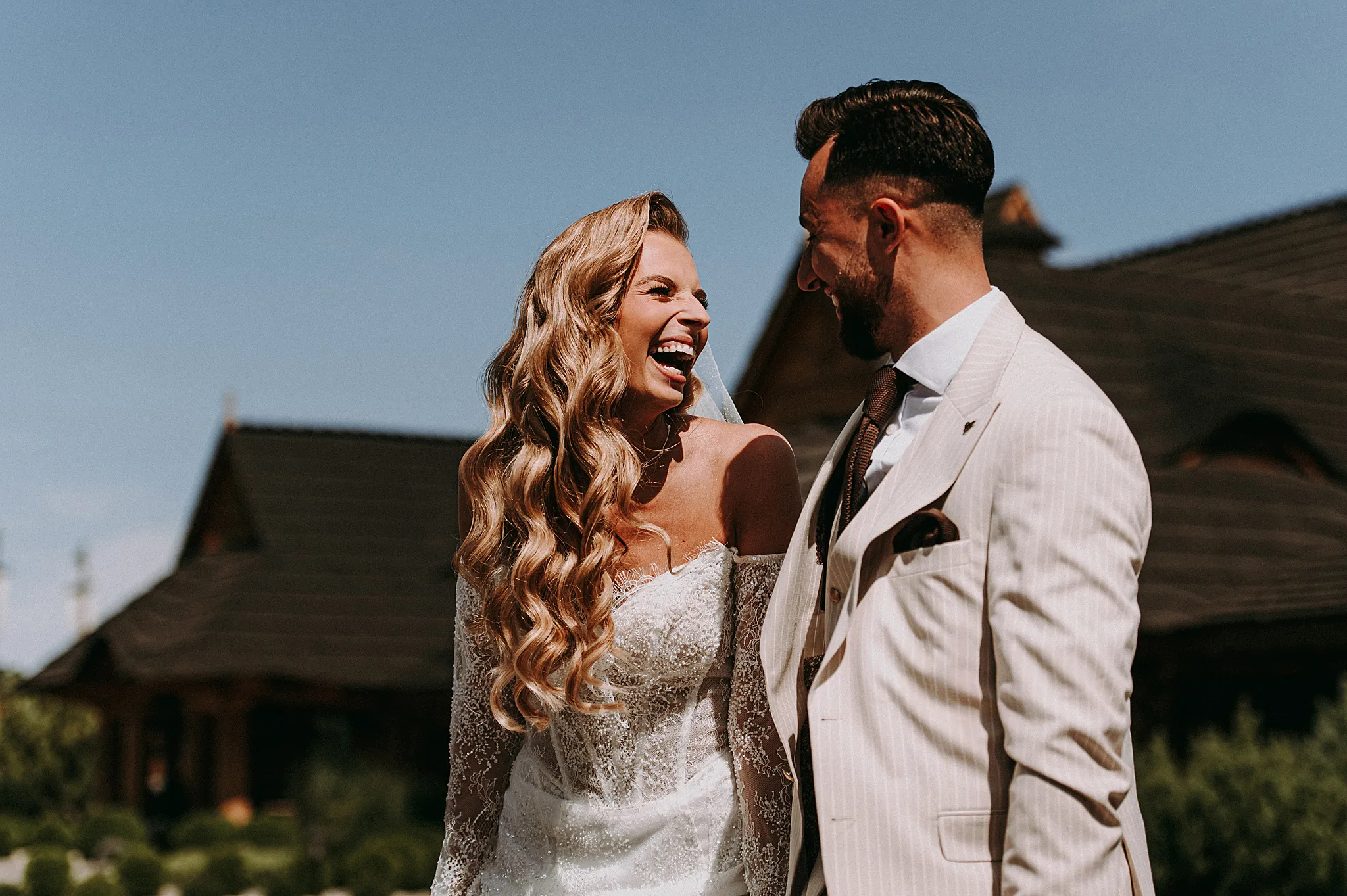 Romantyczne ujęcie pary młodej w złotym świetle na tle białych dekoracji i zielonego ogrodu