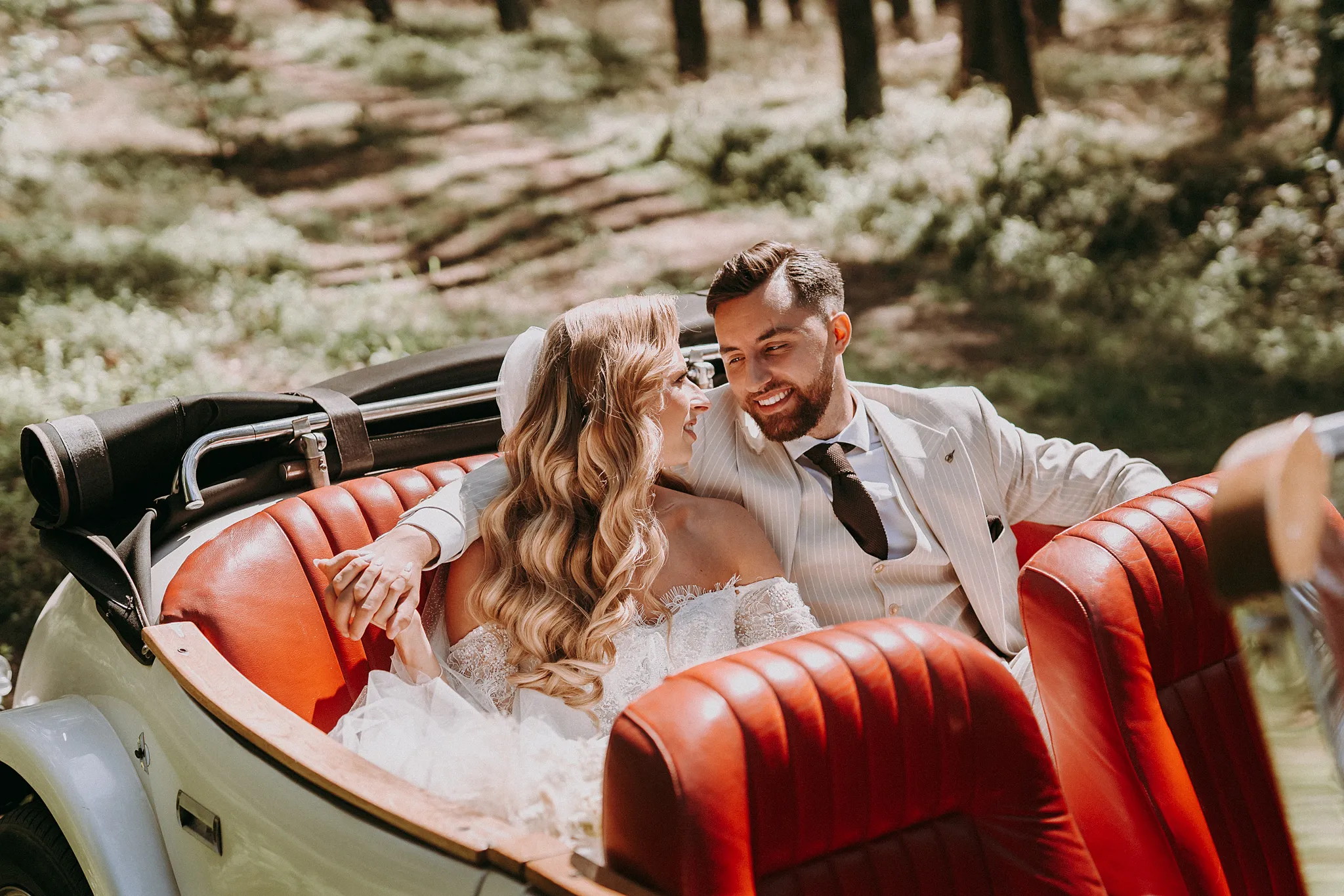 Para młoda siedząca w środku zabytkowego auta, patrząca na siebie z miłością – zdjęcie grygierczyk.com