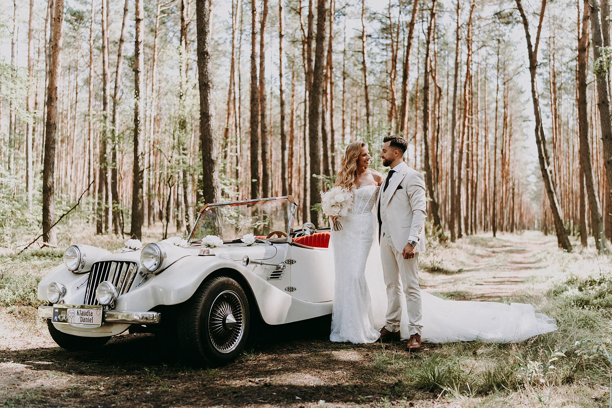 Nowożeńcy pozujący przy zabytkowym samochodzie retro zaparkowanym w malowniczej okolicy Hotelu Bajka – fot. Studio Grygierczyk