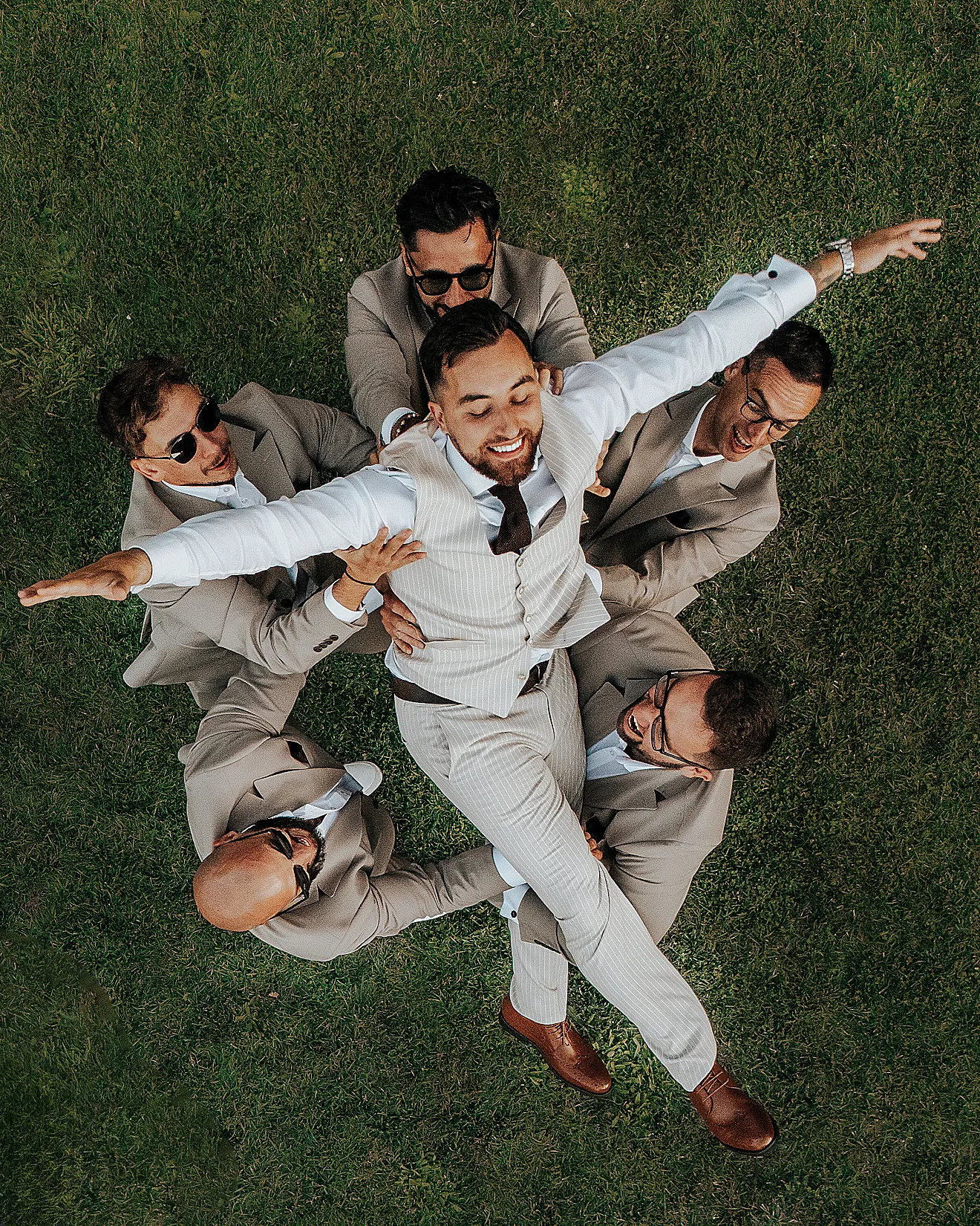 Dynamiczne ujęcie: drużbowie podrzucają roześmianego pana młodego w górę na tle ogrodu w Hotelu Bajka – fot. Studio Grygierczyk