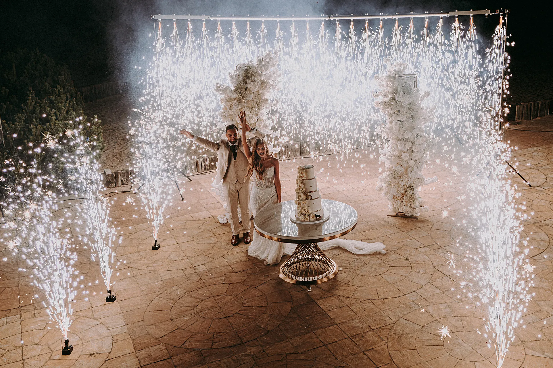 krojący tort w otoczeniu fontann iskier (zimnych ogni) nad wodą, uchwycone przez Studio Grygierczyk