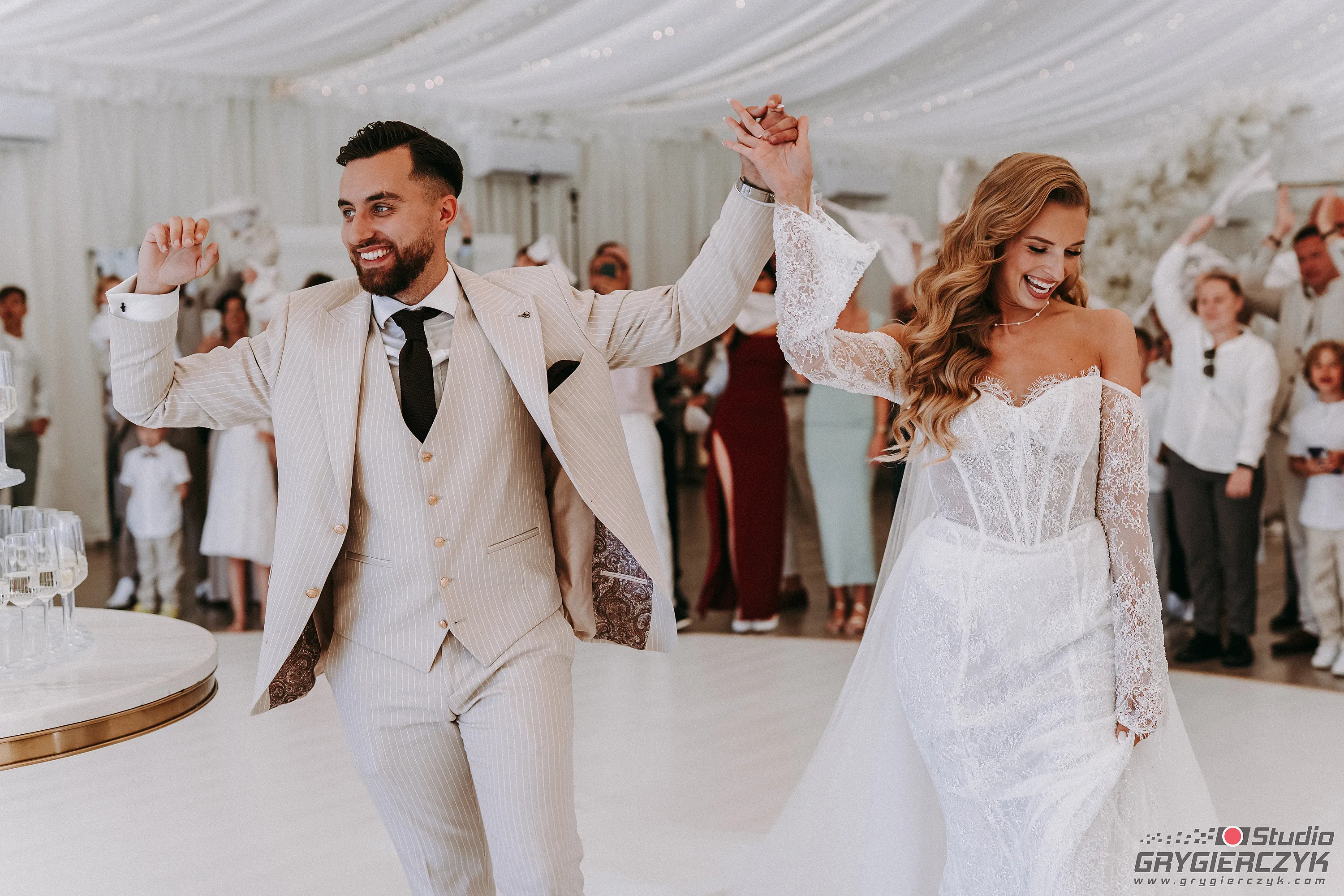 Szalone wejście pary młodej do namiotu weselnego  – goście wiwatują, machając białymi chusteczkami