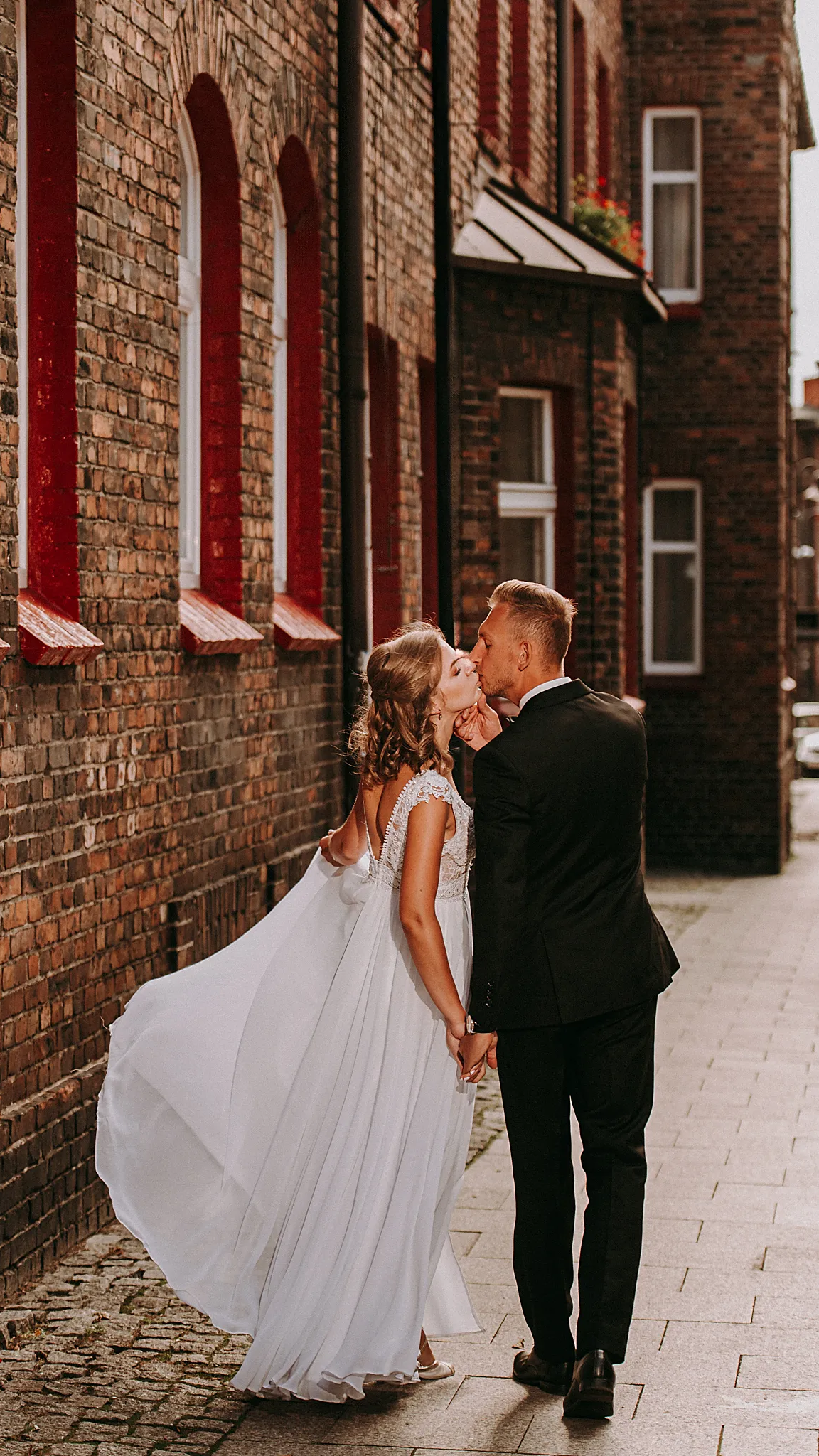 pan mlody caluje mloda pania podczas spaceru na zabytkowej dzielnucy nikiszowca w godzinach kiedy zahodzi slonce golden hour