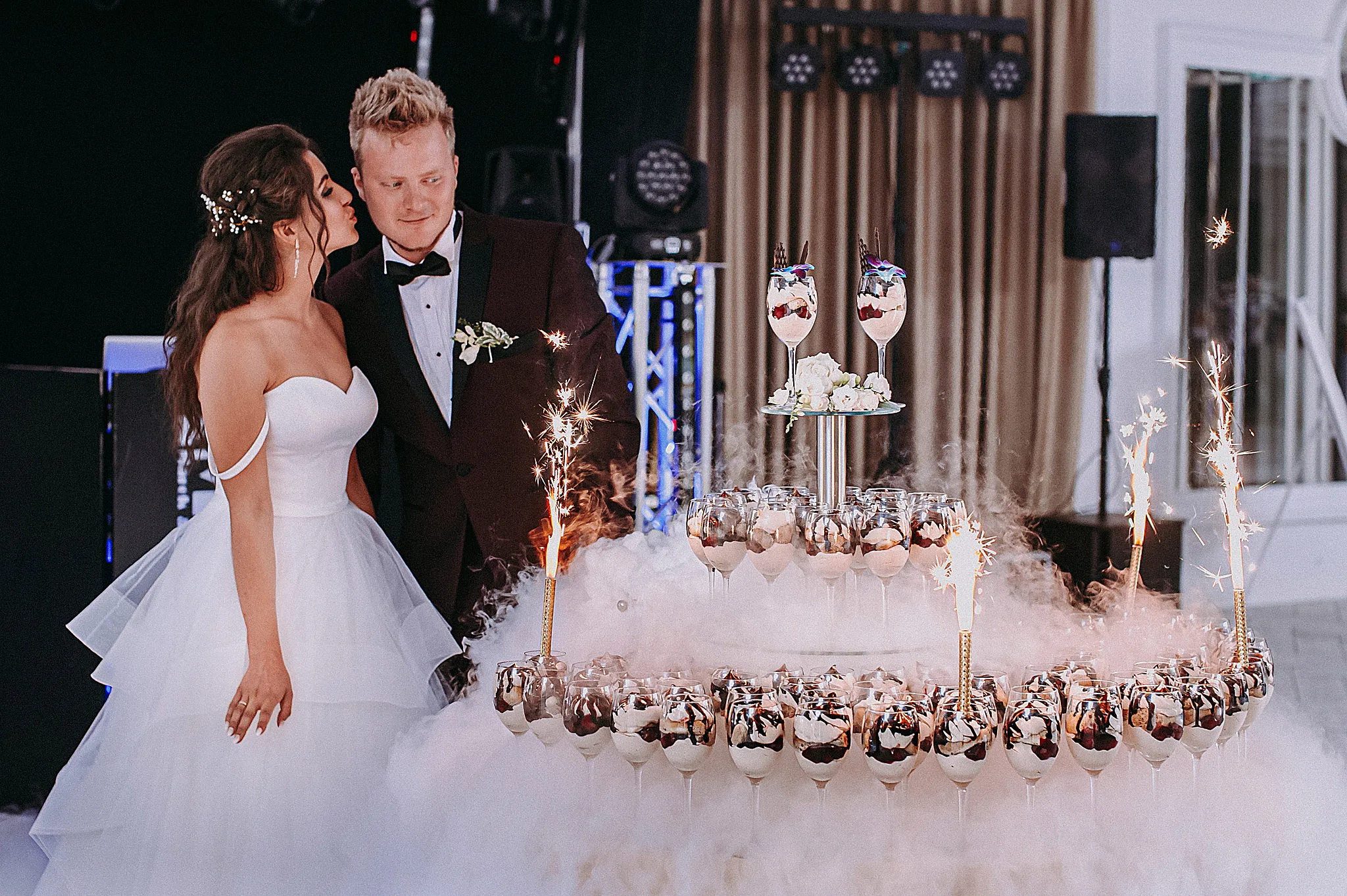 oryginalny tort weselny na sali weselnej z plonacymi racami w kieliszkach