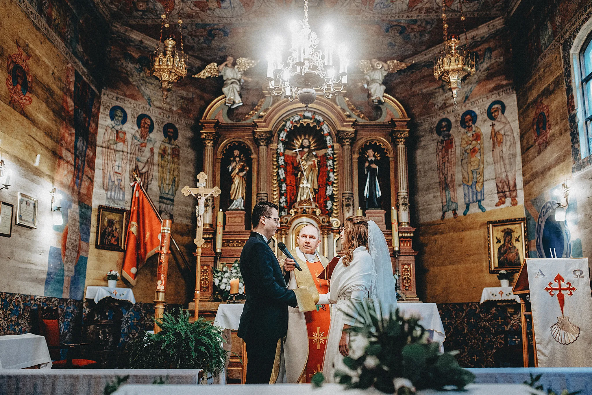 wzruszona para mloda stoi w kosciele swietego jakuba w szczyrku na tle zabytkowego oltarza