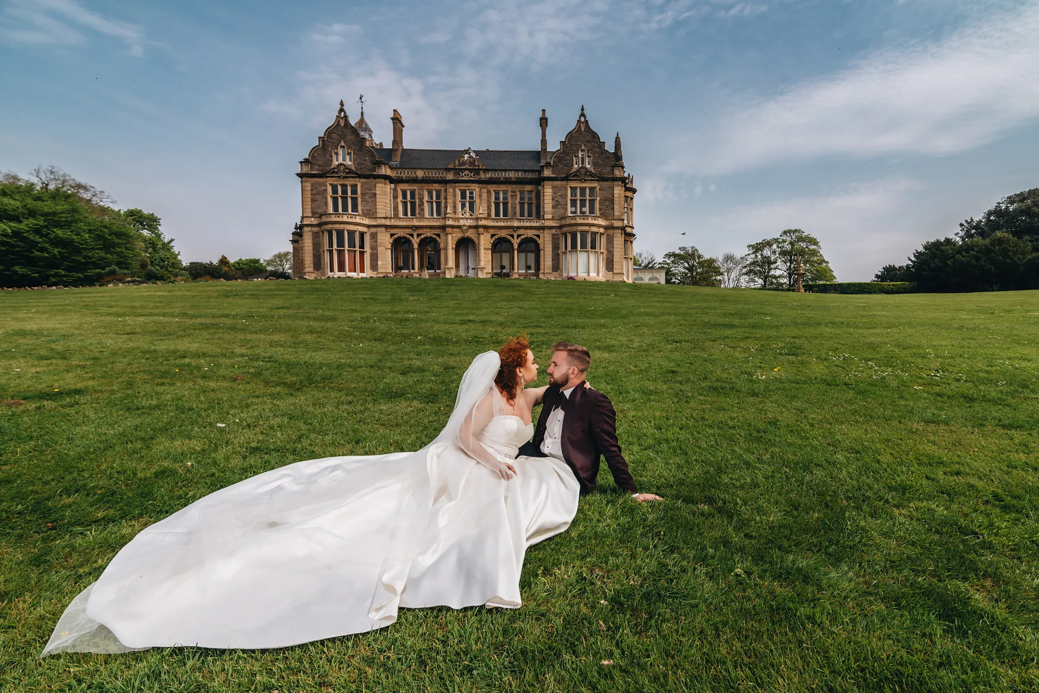 para mloda chillujaca na trawie przed palacem w uk. sesjje slubne zagraniczne studio grygierczyk